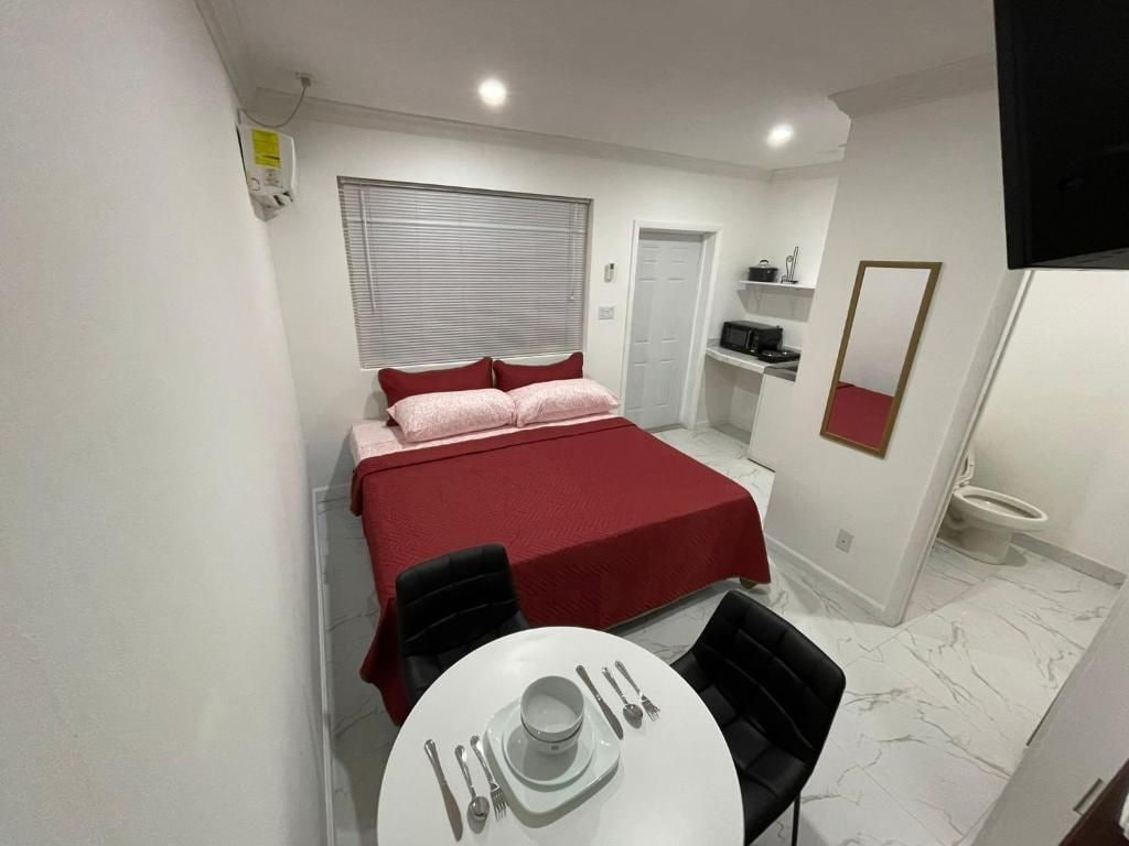 Ein Hotelzimmer mit einem Bett, einem Esstisch mit Besteck, einer Mikrowelle und einem WC.