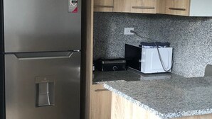 Een keuken met een roestvrijstalen koelkast, houten kastjes, granieten aanrecht en een inbouwoven.