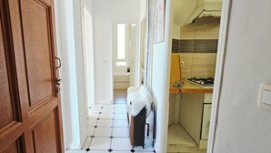 A hallway with a tiled floor leading to a kitchen area with a stove and a sink. - Apartment: Les Senteurs de Grasse (Grasse)