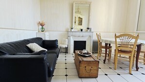 A living room with a black leather sofa, a wooden chest of drawers, a dining table with chairs, and a fireplace. - Apartment: Les Senteurs de Grasse (Grasse)