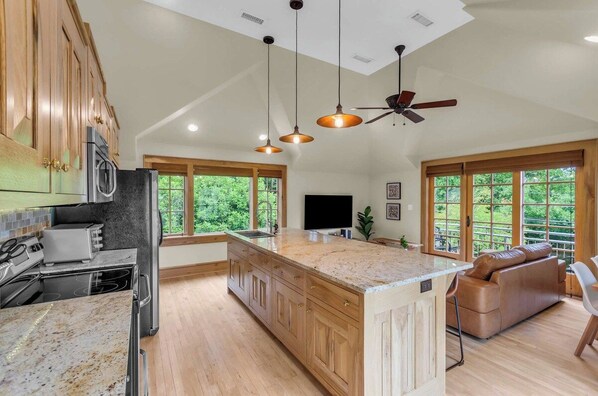 A spacious kitchen with wooden cabinets, a large island, and a ceiling fan.