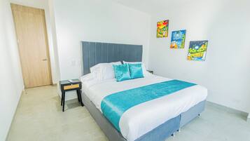 Un dormitorio con cama, mesita de noche, puerta de madera y tres adornos en la pared.
