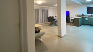 A spacious living area with a dining table and chairs, a sofa, and a kitchen area with a counter and cabinets.