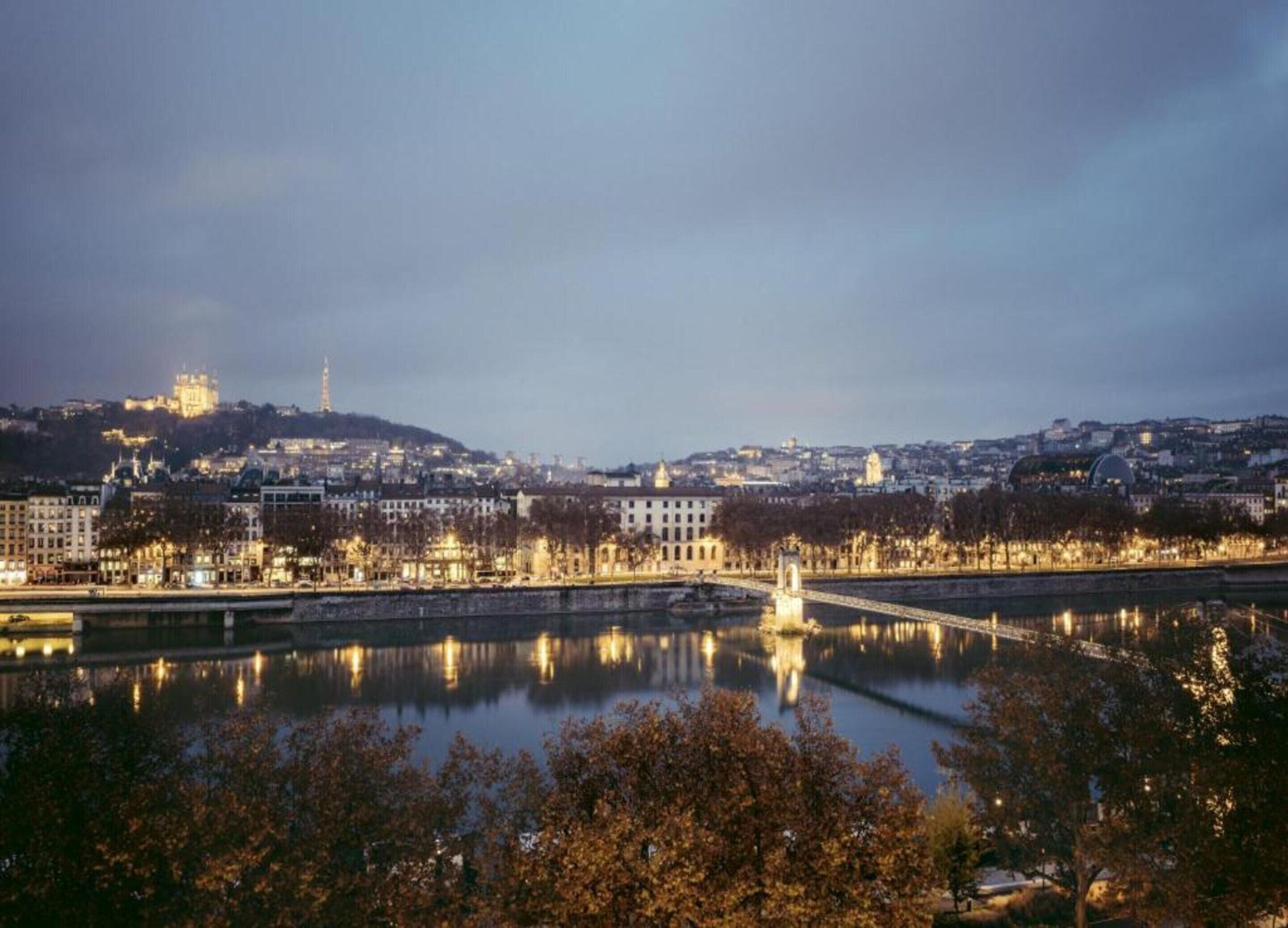 A cityscape with a river, buildings, and a hill with a castle-like structure.