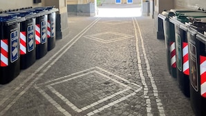 A corridor with trash bins, a tiled floor, and an archway leading to a building with a sign. - Napoli Heart and Suite (Naples)
