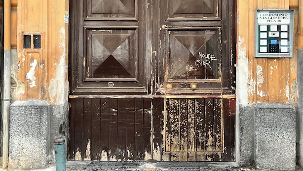 A large wooden door with a glass panel, a security camera, and a sign indicating a condominium. - Napoli Heart and Suite (Naples)