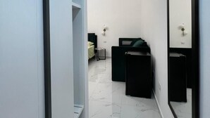 A modern bathroom with a large mirror, a black vanity, and a green chair. - Napoli Heart and Suite (Naples)
