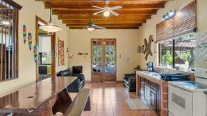 Una cocina amplia con techo de madera, una zona de comedor con una mesa larga y una encimera de cocina con fregadero y horno.