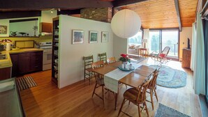 Une cuisine spacieuse avec des meubles de rangement en bois, un coin repas avec une table et des chaises en bois, et un grand plafond en bois.