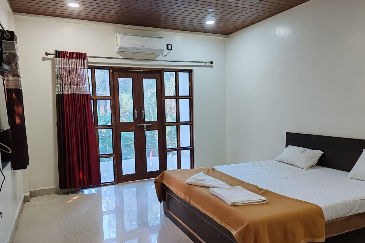 A bedroom with a bed, a window with curtains, and an air conditioning unit.