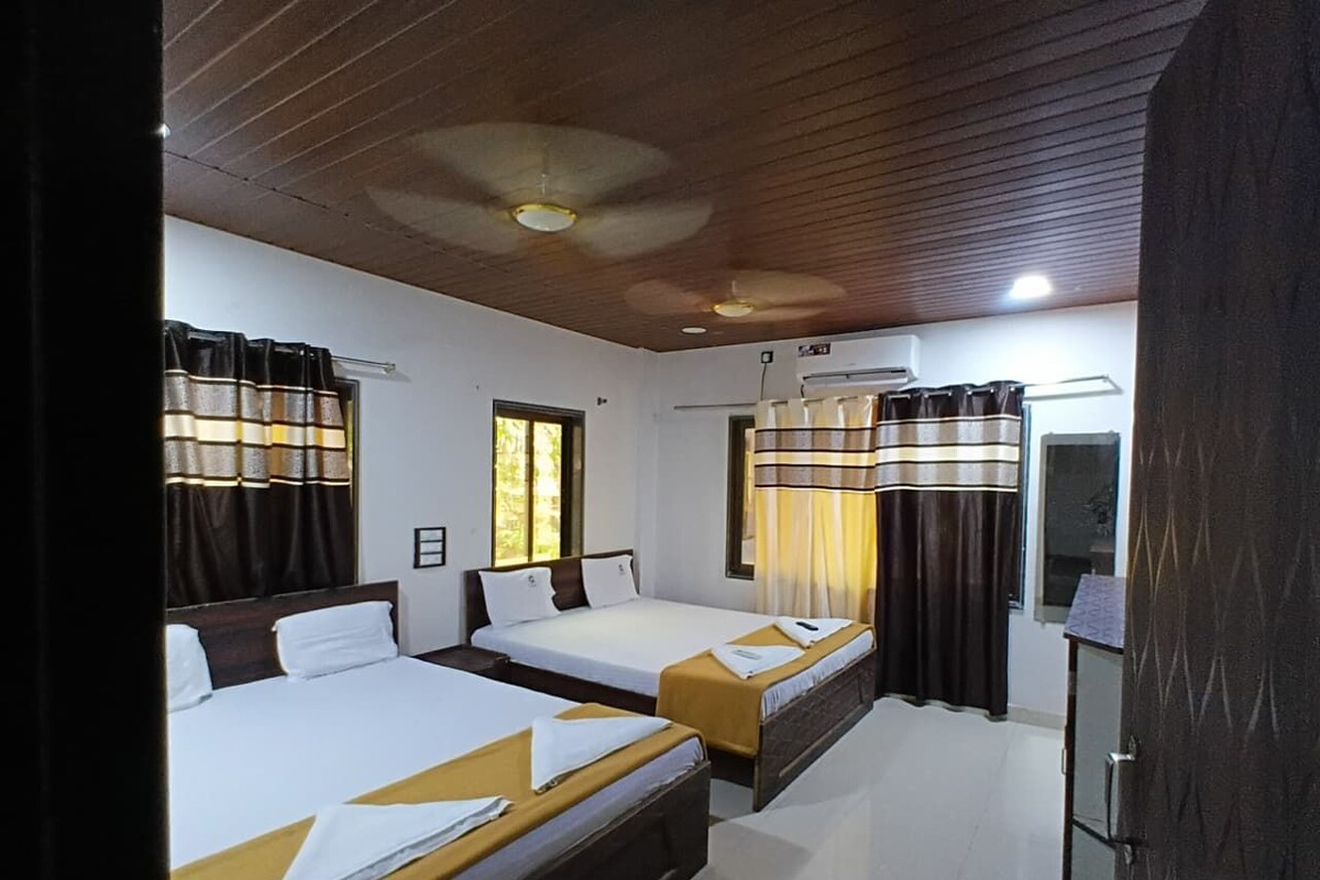 Habitación de hotel con tres camas individuales, ventilador de techo y ventana con cortinas.