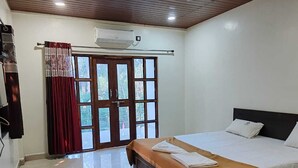 Ein Schlafzimmer mit einem Bett, einem Fenster mit Vorhängen und einer Klimaanlage.
