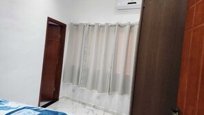 A bedroom with a bed, a shower curtain, and an air conditioning unit. - Perequê-Açú - 200m from the beach • Air conditioning • Grill • 8 Guests (Perequê-Acu Ubatuba)
