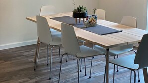 Un coin repas comprenant une table rectangulaire, six chaises, un miroir rond et un luminaire suspendu.