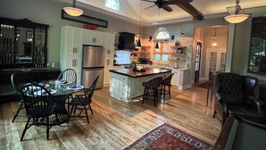 A spacious kitchen with high ceilings, a central island, and a dining area with chairs.