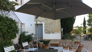 Eine Terrasse im Freien mit Tisch und Stühlen, umgeben von Blumentöpfen und einer Steinmauer.