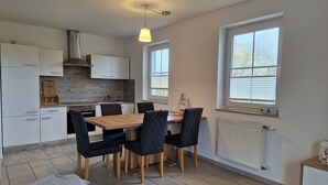 A modern kitchen with a dining table, chairs, and a hanging light fixture.
