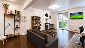 A modern living room with a sofa, a bookshelf, a fireplace, and a TV.
