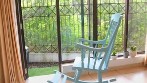 A rocking chair in a room with a large window overlooking a garden.