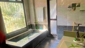 A modern bathroom with a large bathtub, a sink, and a shower.