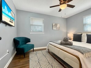 A bedroom with a bed, a chair, a ceiling fan, and a painting on the wall. - Charming Southern Retreat in Rincon – Near Savannah (Rincon)