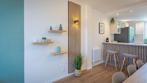 Une cuisine moderne avec des étagères en bois, des tabourets de bar et une plante en pot.