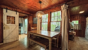 A rustic wooden interior with a wooden table, bench, and a hanging light fixture.