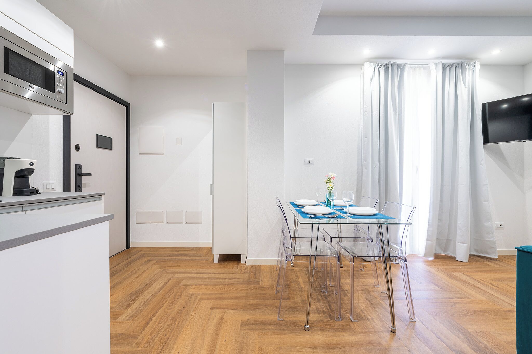 Une cuisine moderne équipée d’un four à micro-ondes, d’une machine à café et d’un coin repas avec une table dressée pour deux personnes.