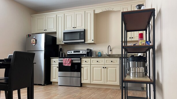 A kitchen with white cabinets, a stainless steel refrigerator, a microwave, an oven, and a coffee maker on a shelf. - Chill Suburban 1BR Hideaway Near Truist Stadium (Mableton)