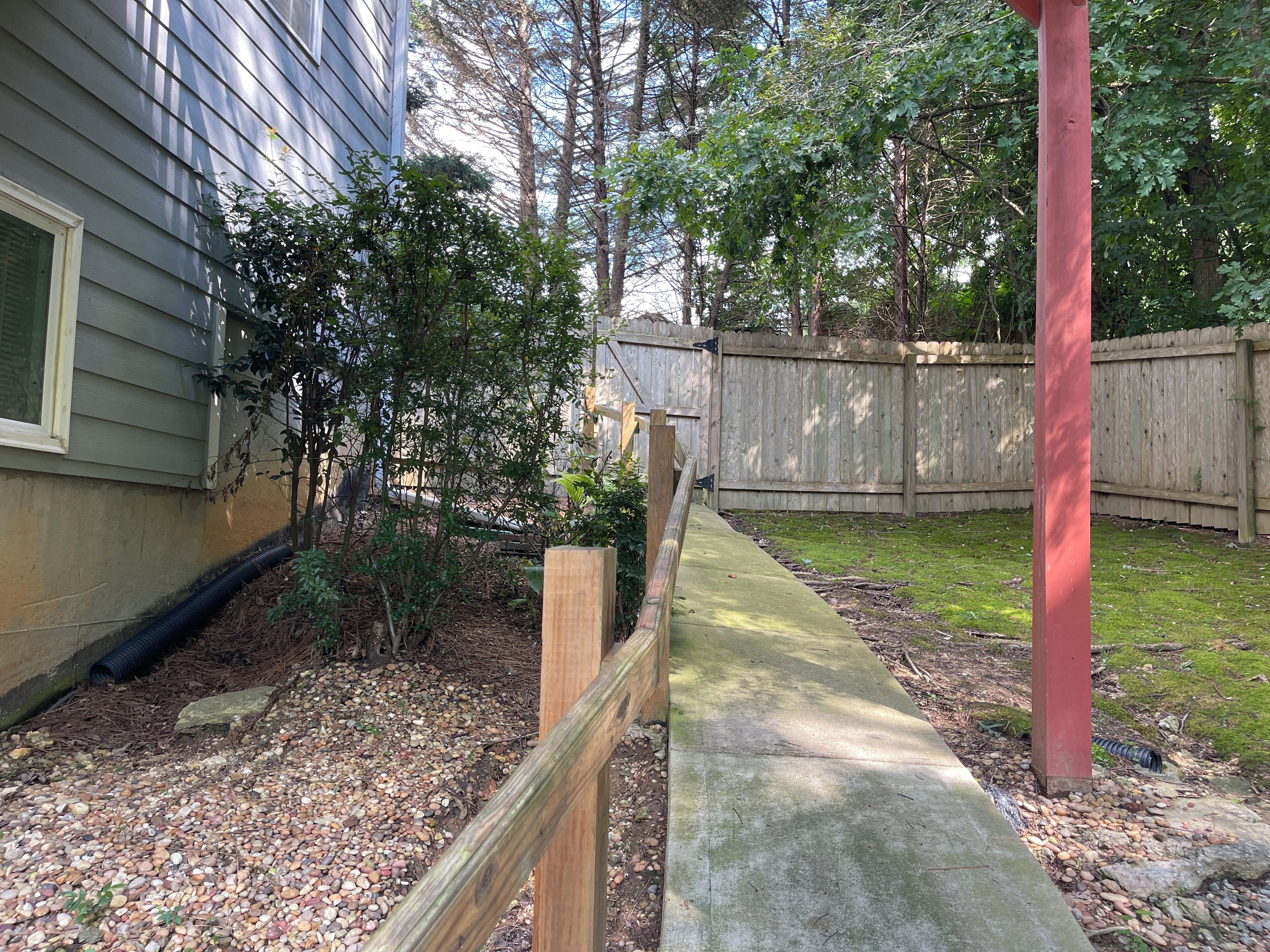 Un jardin avec une terrasse en bois, une clôture en bois et une maison recouverte de bardage.