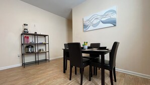 A dining area with a table and chairs, a bookshelf, and a painting on the wall. - Chill Suburban 1BR Hideaway Near Truist Stadium (Mableton)