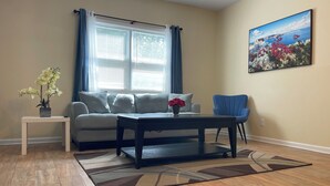A living room with a sofa, coffee table, and a painting on the wall. - Chill Suburban 1BR Hideaway Near Truist Stadium (Mableton)
