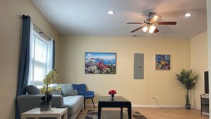 A living room with a ceiling fan, a sofa, a coffee table, and a painting on the wall. - Chill Suburban 1BR Hideaway Near Truist Stadium (Mableton)