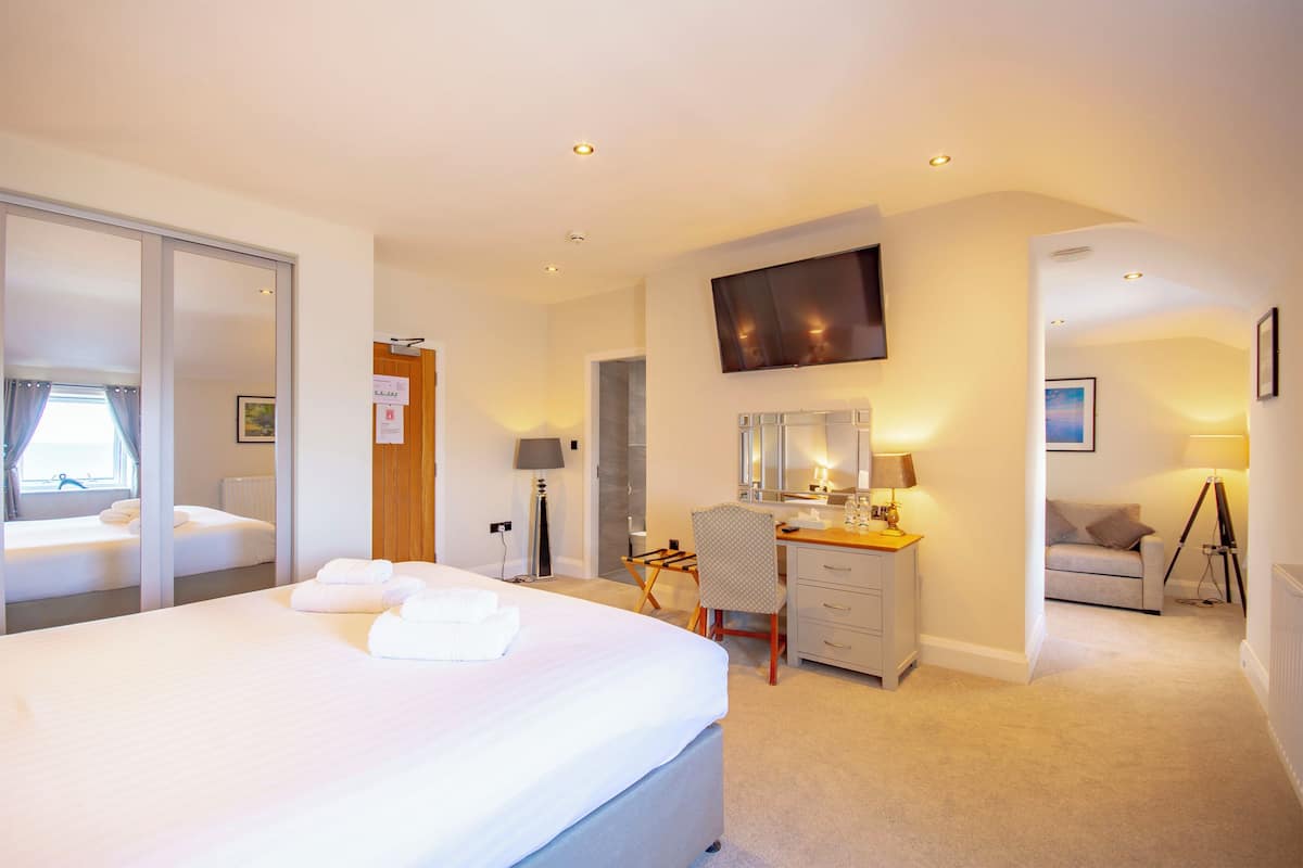 A hotel room with a bed, desk, chair, TV, and a view of the outside.