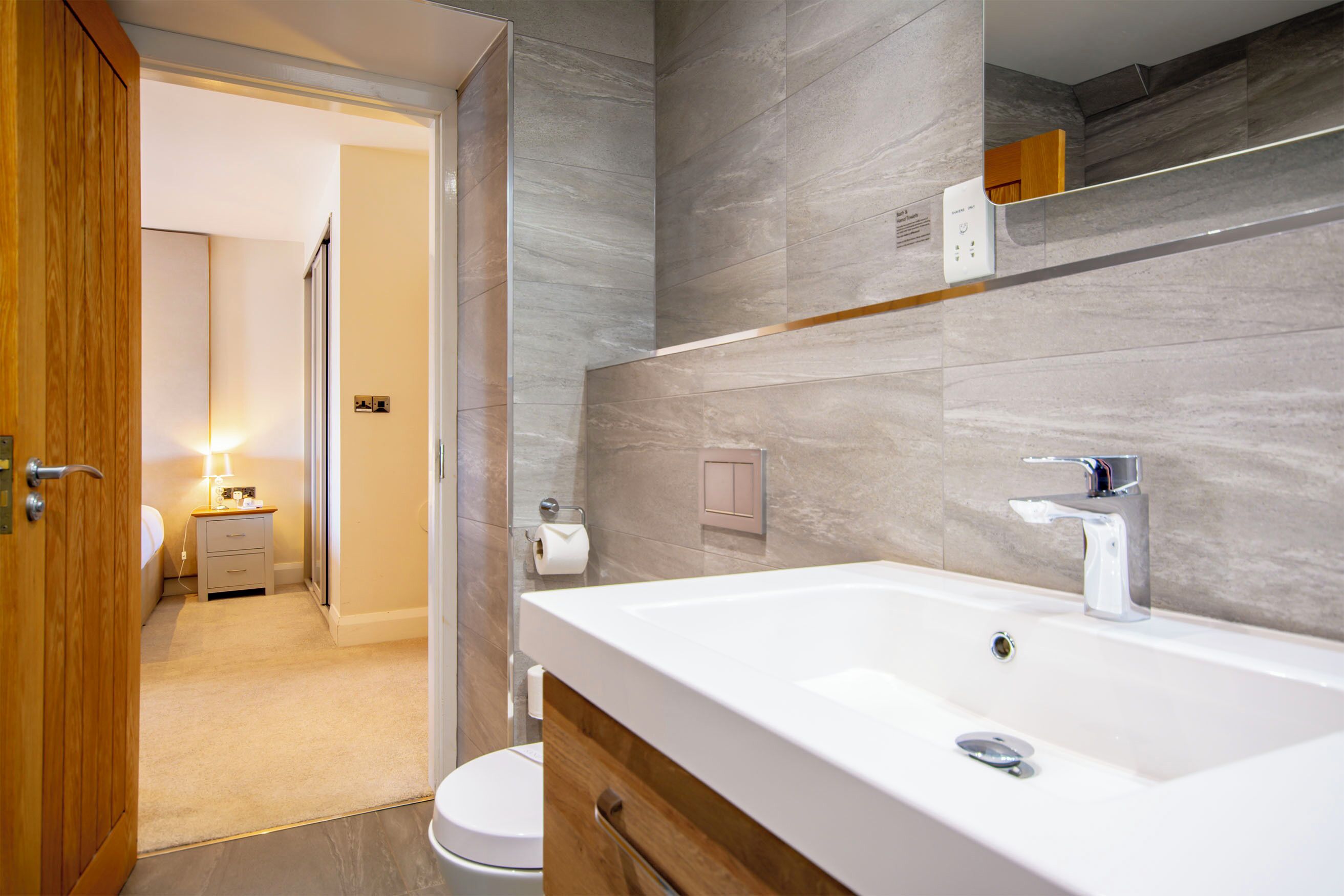 A modern bathroom with a large sink, a mirror, and a toilet.