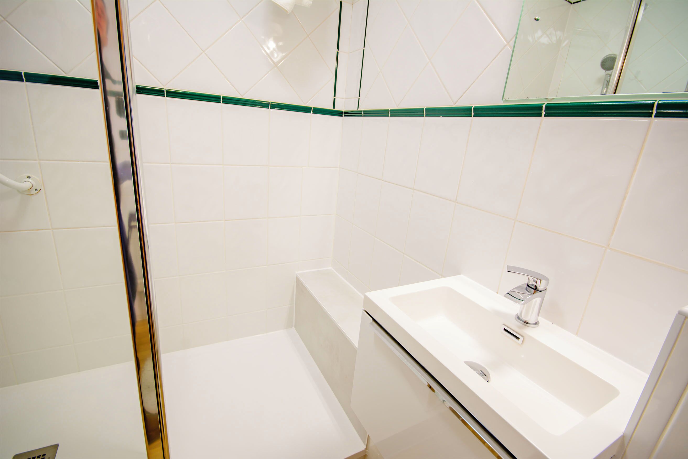 Une salle de bain avec une douche, un lavabo et un miroir.