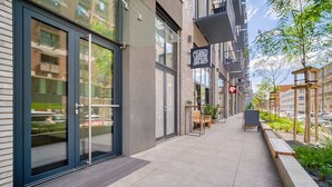 A modern building with a glass entrance, outdoor seating, and a sign for 'TOUSSA'.