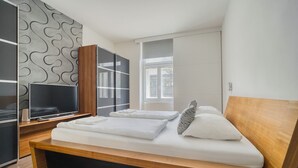 Une chambre à coucher moderne avec un lit en bois, une télévision et une armoire.