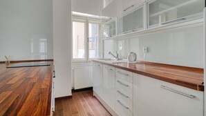 Une cuisine moderne avec un plancher en bois, des meubles blancs et une fenêtre qui laisse entrer la lumière naturelle.