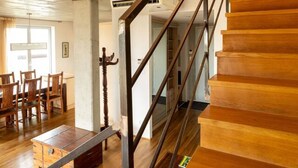 Una escalera de madera con barandilla de metal que conduce a una puerta.