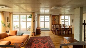 Un salón amplio con sofá, una mesa de comedor con sillas y un ventanal que ofrece vistas al exterior.