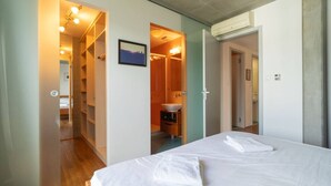 Una habitación de hotel con cama, baño y un pasillo que da a otra habitación.