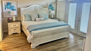 A bedroom with a white bed, a nightstand, a ceiling fan, and artwork on the walls. - Homey lakefront condo on quiet cove in Hot Springs (Hot Springs)