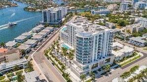 A high-rise hotel with a pool, surrounded by a marina and other buildings. - 5-Star Luxury Condo at Tiffany House, two rooftop pools, one block from beach (Fort Lauderdale)