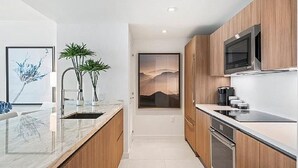 A modern kitchen with wooden cabinets, a built-in microwave, and a large window with a mountain view. - 5-Star Luxury Condo at Tiffany House, two rooftop pools, one block from beach (Fort Lauderdale)