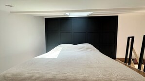 Ein Schlafzimmer mit einem Bett, einem dunklen Kopfteil und einem Dachfenster.