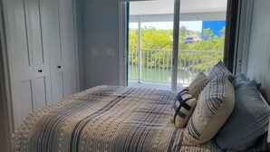 A bedroom with a bed, a large window, and a view of greenery outside. - Cozy Keys Hideaway on the water (Tavernier)