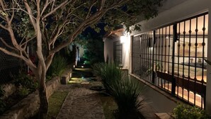 A nighttime view of a pathway leading to a gated entrance with a house in the background.
