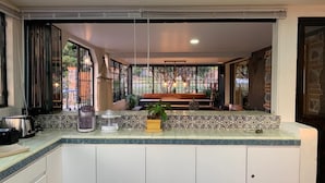A kitchen with a large window, a countertop with a coffee maker, and a plant.