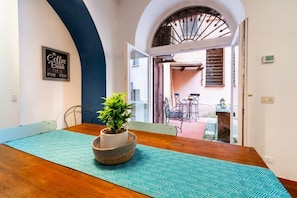 A dining area with a wooden table, a potted plant, and a blue patterned table runner. - Number Five Apartment in Trastevere (Roma)
